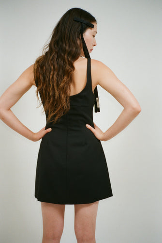A model wears long taffeta bows against a grey background
