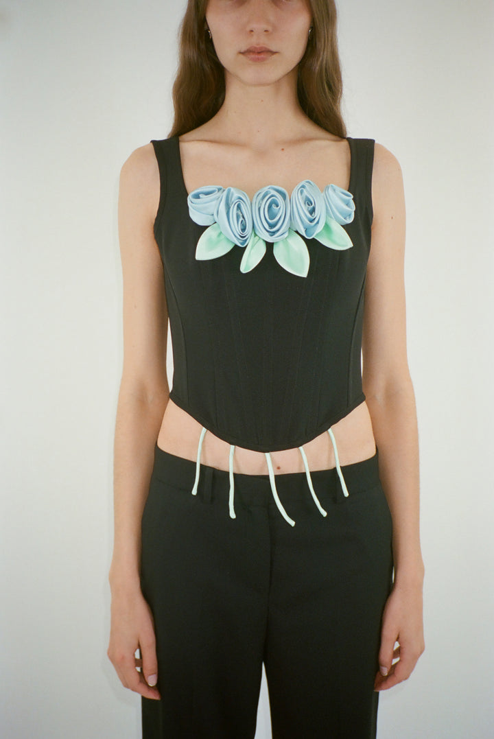 Structured corset in black with blue roses at front on model
