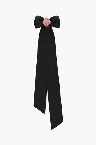 A black crepe hair bow with pink satin rosette attached to a French barrette, with elongated tails.