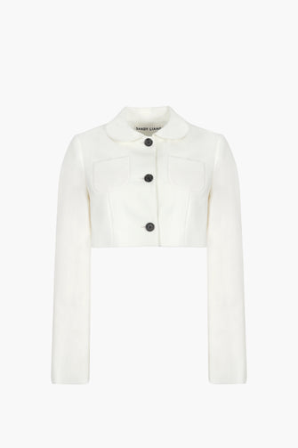 Cropped tailored jacket in Bone mid weight suiting with long bows at back, chest pockets, and button closure against a white background.