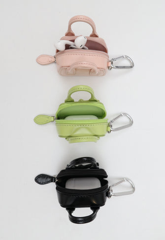 Three small keychain bags in pink, green, and black on a white background