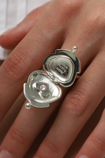 Silver ring with a heart-shaped locket on a hand