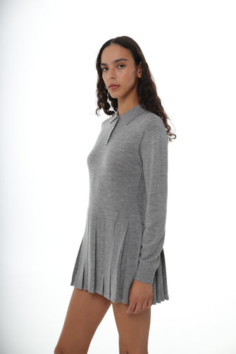 A woman wears a mini sweater dress in gray with long sleeves, a collar, and mother of pearl buttons against a white background