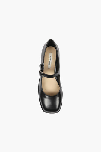 Black spazzolato leather Mary Jane shoes with a buckle closure and a stacked heel against a white background