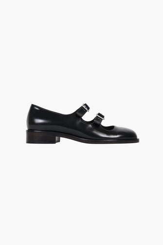 Black Mary Jane double strap shoes with a polished leather finish, featuring adjustable pin-buckle straps and a low heel against a white background