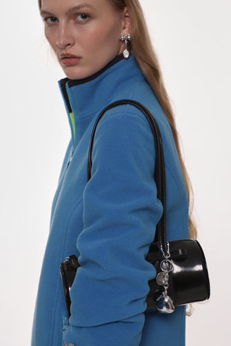 model wearing blue sweater and black bag with silver keychain