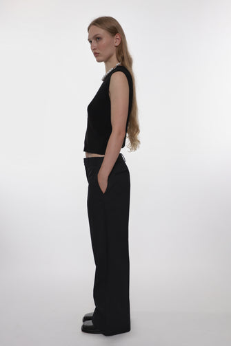 Woman wearing a black sleeveless top and black pants on a white background