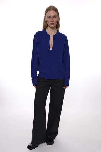 Person wearing a blue top and black pants on a white background