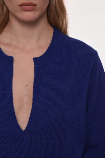 Close-up of a person wearing a blue sweater with a deep neckline.