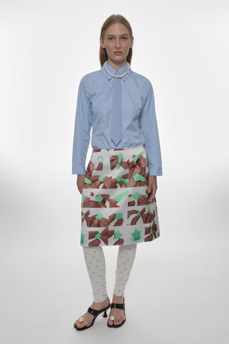 model wearing blue shirt and white satin midi skirt with folding origami photo pattern