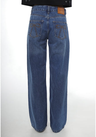A woman in a pair of blue denim jeans with bow embroidery on the back pockets against a white background
