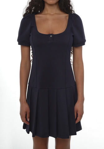 A woman wears a navy-colored dress with short puffed sleeves, a round neckline, and a flared skirt. The dress features button details and a fitted waist against a white background