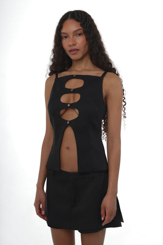 Woman wearing a black sleeveless top with cut outs on torso paired with a black mini skirt
