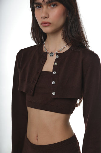 Person wearing a brown merino wool cardigan layered over a merino wool tank top on a white background