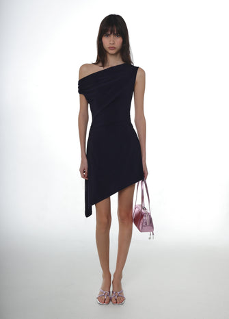 Woman wearing a navy one-shoulder dress holding a pink handbag on a white background