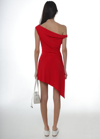 Woman wearing a red one-shoulder dress with an asymmetrical hem holding a white handbag and wearing white shoes on a white background