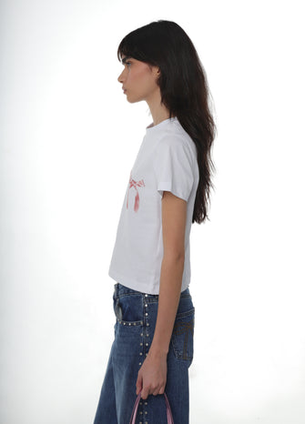 A woman is standing, wearing a white crew neck t-shirt paired with blue jeans against a white background