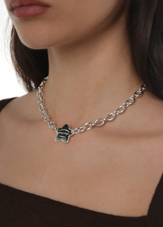 Close up of a woman wearing a silver cable chain necklace with a star charm