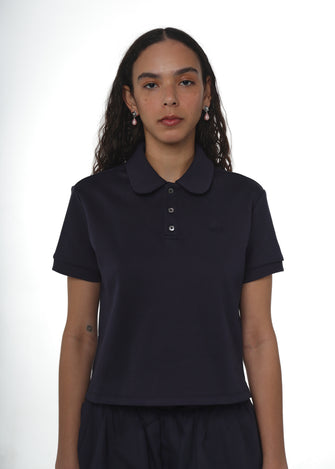 A woman wearing a navy-colored polo shirt with a collar, short sleeves, and button-up front.