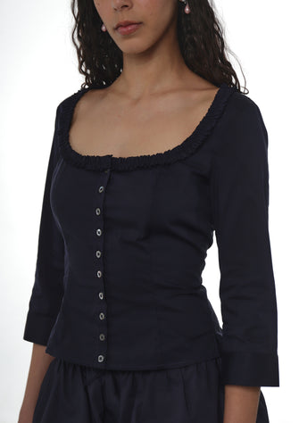 Close up of a woman wearing a Navy top with buttons on a white background