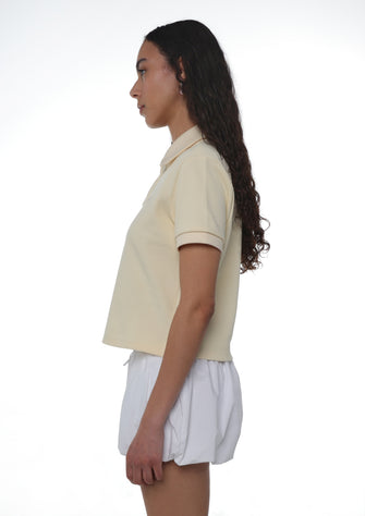 Person wearing a beige polo shirt and white shorts on a white background