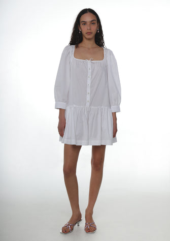 Woman wearing a white dress on a plain background