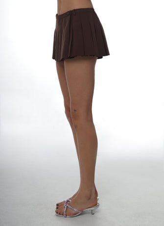 Close up of someone wearing a brown micro mini pleated skirt and silver sandals