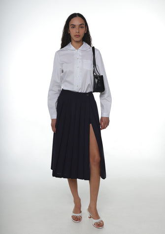 A model wears a pleated midi length dark navy skort with built-in shorts. on a white background