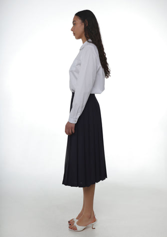 A model wears a pleated midi length dark navy skort with built-in shorts. on a white background
