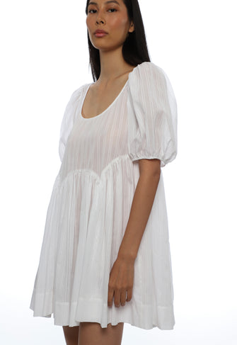 Woman wearing a white babydoll dress on a white background