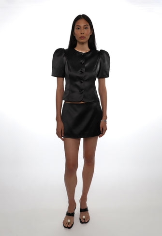 Woman wearing a black outfit with puff sleeves on a white background