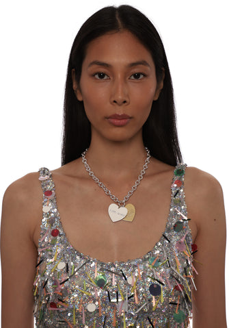 Woman wearing a sparkling top and silver necklace with silver and gold heart pendants on a white background