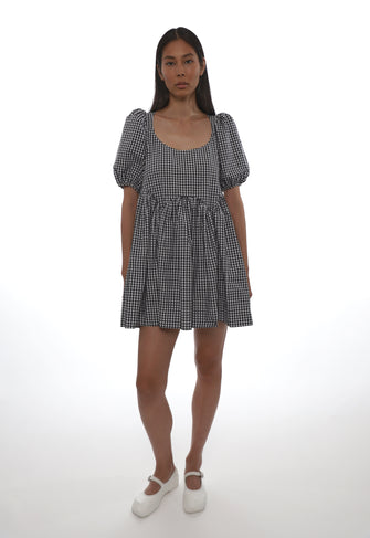 Woman wearing a black and white checkered babydoll dress on a white background