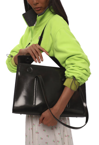 Person holding a black leather bag putting laptop in the bag with a white background