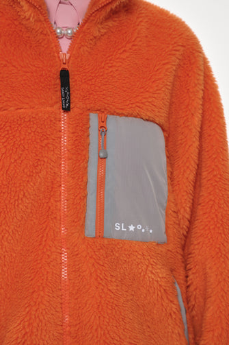 Orange fleece jacket with gray zipper pocket on a white background