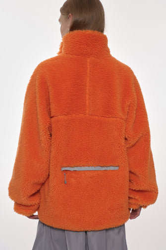 Person wearing an orange fleece jacket on a white background