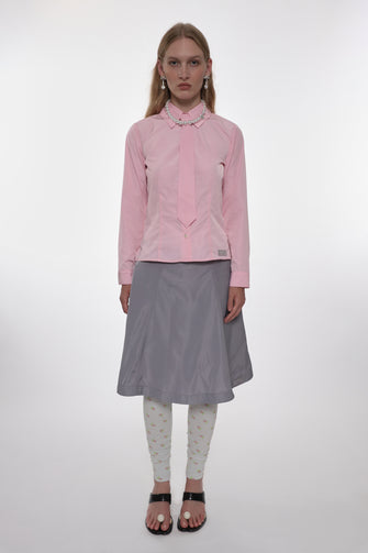 Woman wearing a pink shirt and gray skirt on a white background