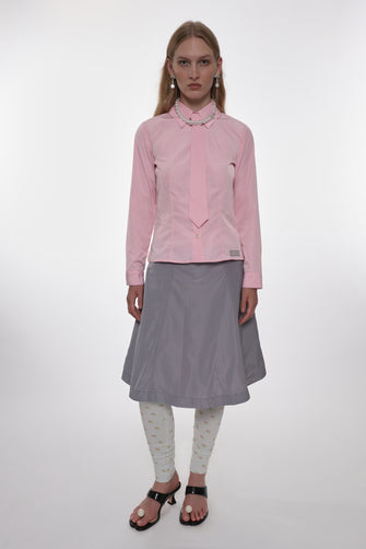 Woman wearing a pink shirt and gray skirt on a white background