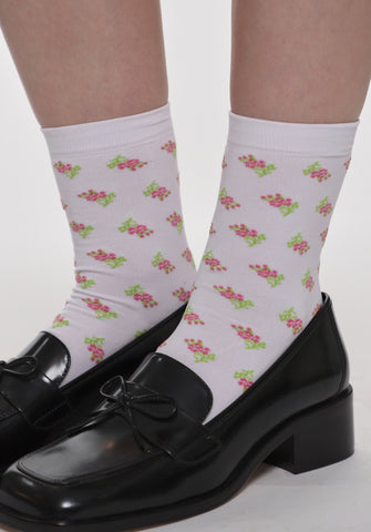 White socks with floral pattern worn with black shoes on a white background