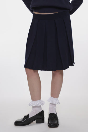 model wearing a navy mid length knit pleated skirt