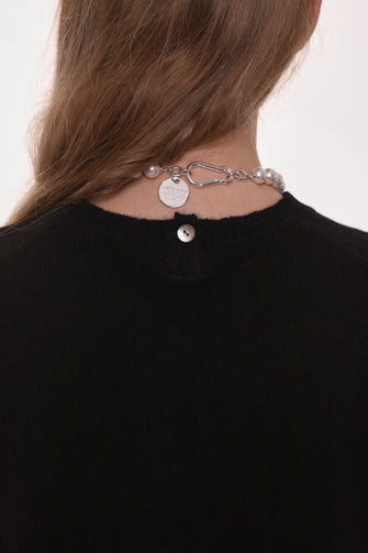 back of a woman wearing a black sweater vest on a white background