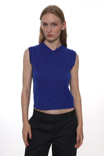 Woman wearing a blue sleeveless top and black pants on a white background