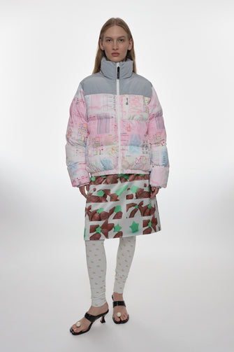 Person wearing a colorful jacket and patterned skirt on a white background