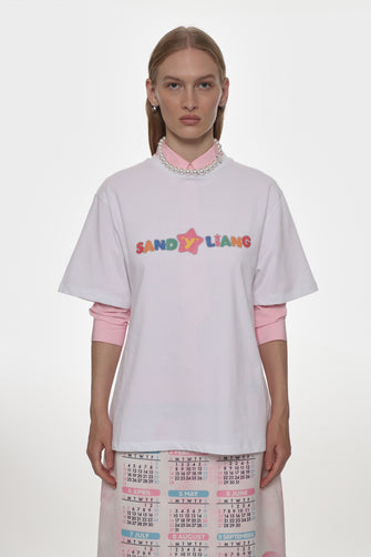 Person wearing a white t-shirt with colorful text layered over a pink shirt on a white background