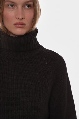 Person wearing a black turtleneck sweater on a white background