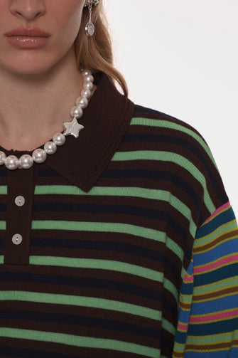 Close-up of a person wearing a striped sweater with a pearl necklace against a white background