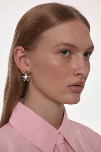 Close-up of a person wearing a star-shaped earring with a plain background