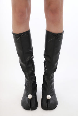 Black knee-high boots with bow details and pearl embellishments on a white background