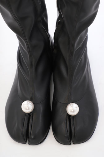 Black knee-high boots with pearl embellishments on a white background