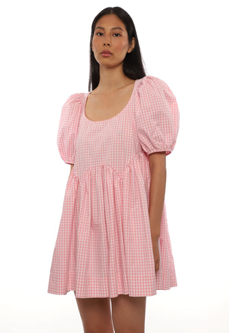 Woman wearing a pink checkered babydoll dress on a white background